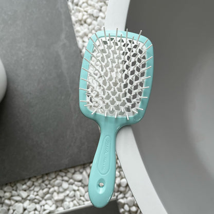 An aqua blue Janeke hairbrush with white bristles on a textured surface