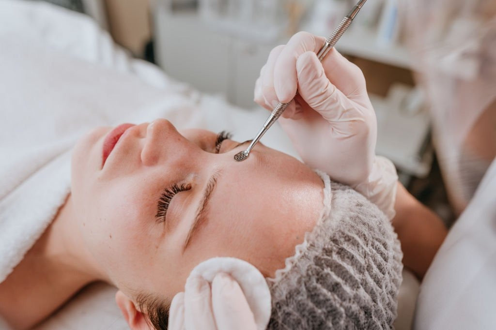 Person receiving a facial treatment with a gloved hand using a tool.