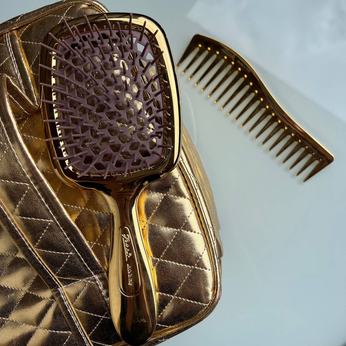 Gold Janeke hairbrush and comb set on a light blue background
