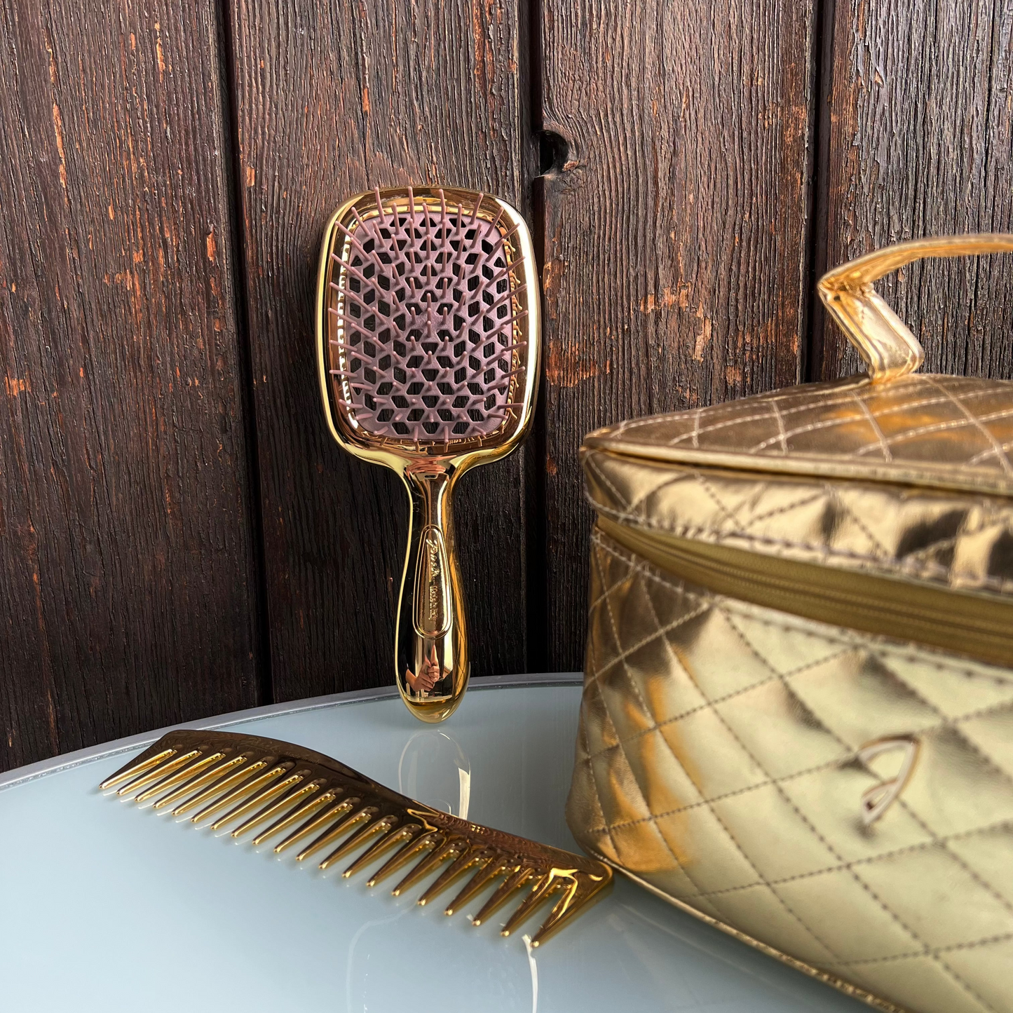 Gold Janeke hairbrush and comb on a light blue surface with a wooden background