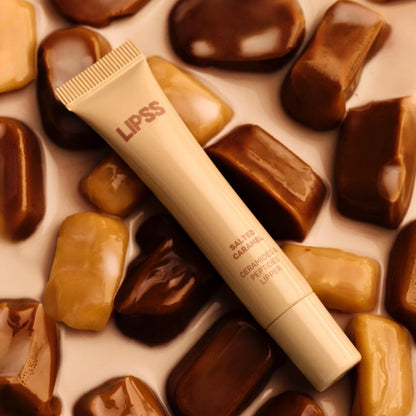 Lip gloss tube lLIPSS Salted Caramel on a background of chocolate candies