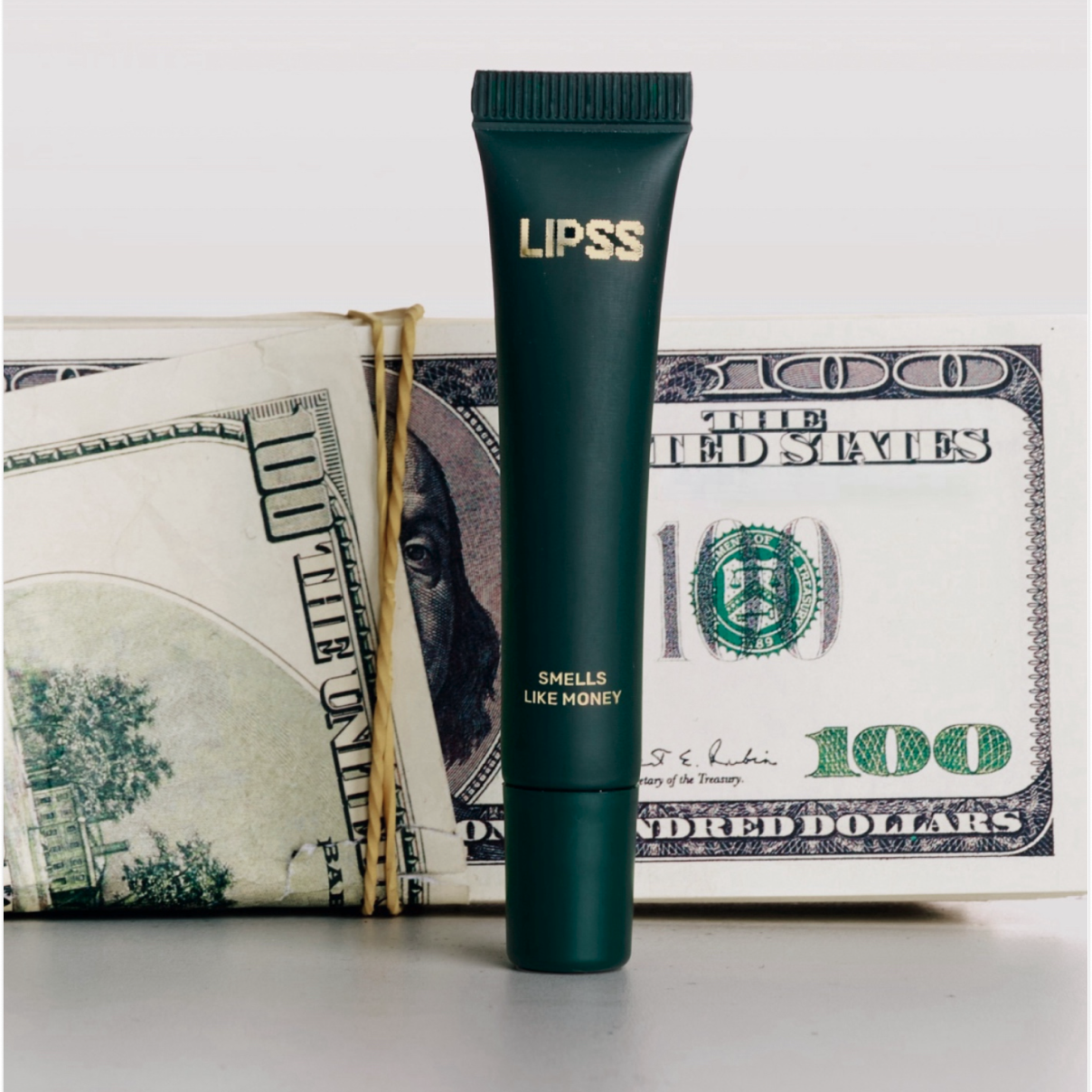 Lip gloss LIPS SMELLS LIKE MONEY on a $100 bill background