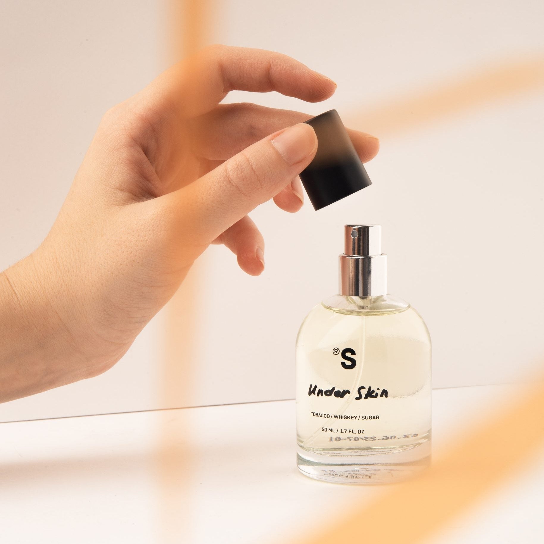 Hand opening a perfume bottle Sister's Aroma 'Under Skin' with a blurred background