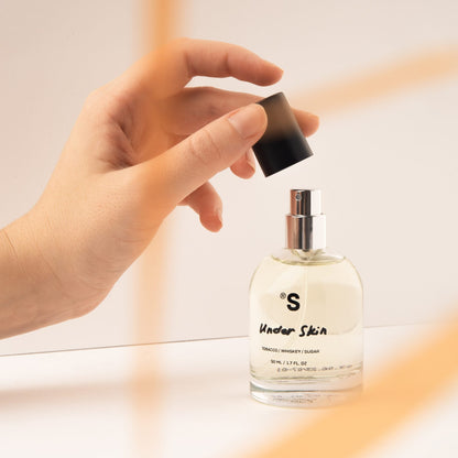 Hand opening a perfume bottle Sister's Aroma 'Under Skin' with a blurred background