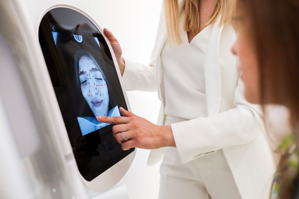 Person using an AI skin analyzer device with a digital display 