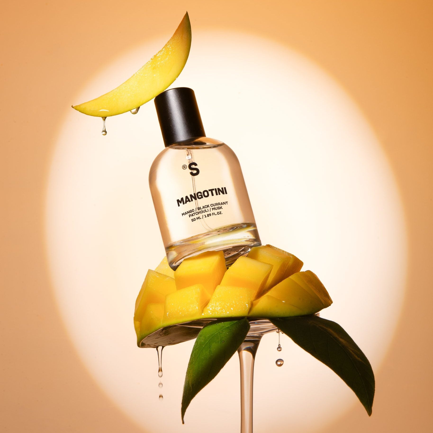 Sister's Aroma Mangotini perfume bottle surrounded by mango slices on a peach background